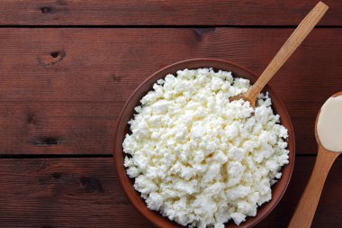 Süzme peynir. Süzme peynir ve krem ahşap kurullarında. Toprak çanak yumuşak beyaz peynir. Süt ürünleri tahta kaşıkla. Kaşığı ekşi krema. Kopya alanı