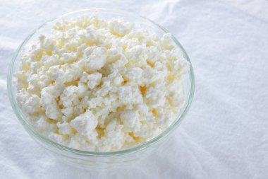 Süzme peynir. Beyaz arka plan üzerinde süzme peynir. Cam beyaz peçete üzerinde suda peynir. Kahvaltıda süt ürünleri. Kopya alanı