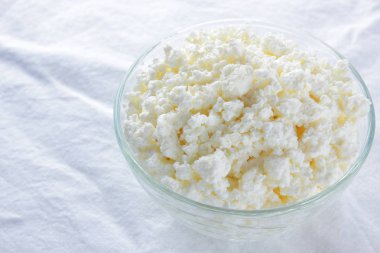 Süzme peynir. Beyaz arka plan üzerinde süzme peynir. Cam beyaz peçete üzerinde suda peynir. Kahvaltıda süt ürünleri. Kopya alanı