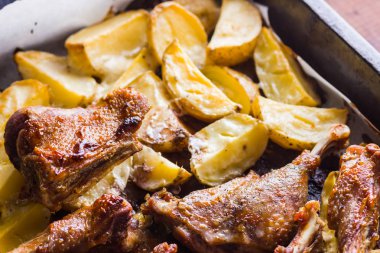 Patates ile pişmiş et. Et sac pişirme üzerinde altın kabuk ile ördek. Fırın çanak parşömen üzerine pişmiş. Tavuk eti ile altın dilimlenmiş patates. Ev mutfak