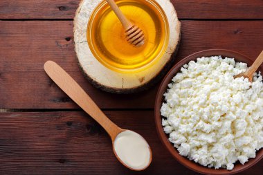 Süzme peynir ve krem. Yumuşak peynir ve bal ahşap kurullarında. Çanak çömlek içinde süzme peynir. Tahta kaşık krem. Ahşap stand tatlım. Kopya alanı