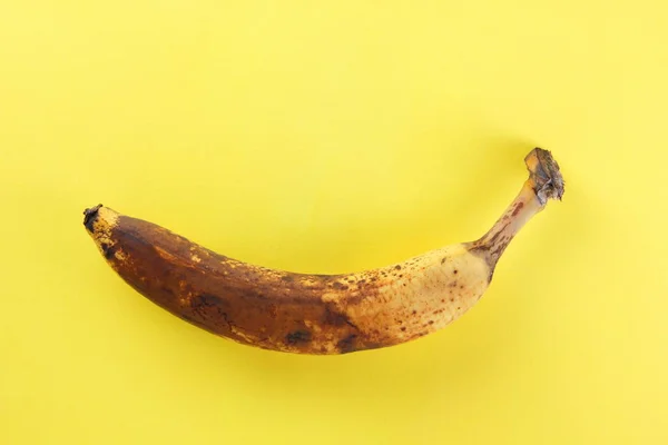 Blackened banana. Banana on yellow background. Spoiled tropical fruit in pop art style. Fruit concept. Source of food poisoning