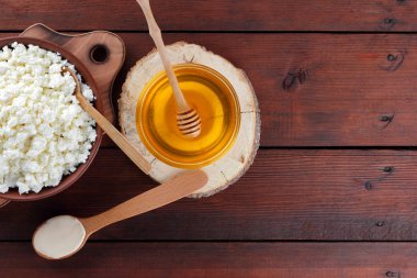 Süzme peynir ve krem. Yumuşak peynir ve bal ahşap kurullarında. Çanak çömlek içinde süzme peynir. Tahta kaşık krem. Ahşap stand tatlım. Kopya alanı