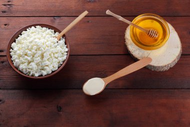 Süzme peynir ve krem. Yumuşak peynir ve bal ahşap kurullarında. Çanak çömlek içinde süzme peynir. Tahta kaşık krem. Ahşap stand tatlım. Kopya alanı