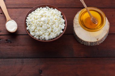 Süzme peynir ve krem. Yumuşak peynir ve bal ahşap kurullarında. Çanak çömlek içinde süzme peynir. Tahta kaşık krem. Ahşap stand tatlım. Kopya alanı