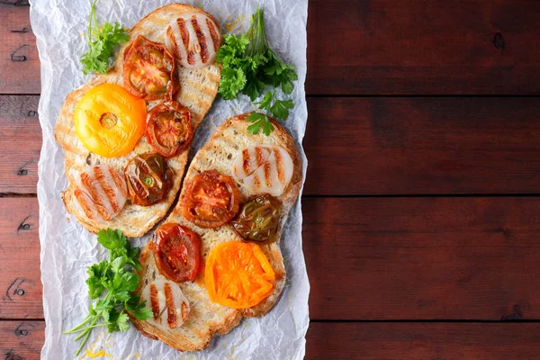 Toast with grilled vegetables. Vegetarian food. Red and yellow tomatoes. Grilled sandwich with tomatoes, onions and herbs. Bread with vegetables and honey. Vegan toast on wooden background