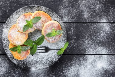 Süzme peynir ile taze nane ile pudra şekeri serpilir krep. Syrniki koyu ahşap kurullarında. Kahvaltı için sağlıklı yemek. Yemek süt ürünleri. Kopya alanı