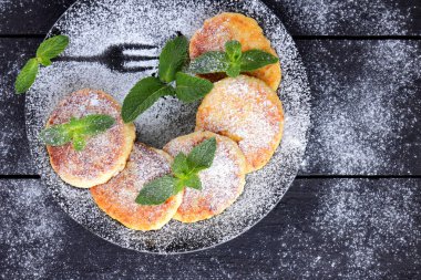 Süzme peynir ile taze nane ile pudra şekeri serpilir krep. Syrniki koyu ahşap kurullarında. Kahvaltı için sağlıklı yemek. Yemek süt ürünleri. Kopya alanı