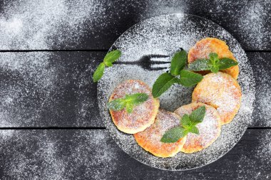 Süzme peynir ile taze nane ile pudra şekeri serpilir krep. Syrniki koyu ahşap kurullarında. Kahvaltı için sağlıklı yemek. Yemek süt ürünleri. Kopya alanı