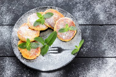 Süzme peynir ile taze nane ile pudra şekeri serpilir krep. Syrniki koyu ahşap kurullarında. Kahvaltı için sağlıklı yemek. Yemek süt ürünleri. Kopya alanı