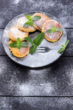 Süzme peynir ile taze nane ile pudra şekeri serpilir krep. Syrniki koyu ahşap kurullarında. Kahvaltı için sağlıklı yemek. Yemek süt ürünleri. Kopya alanı