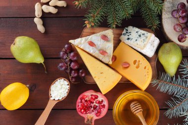 Çeşitli tür peynir meyve ve ahşap kurullarında tatlım. Noel ağacı dalı. İsviçre peyniri, mavi peynir, camembert ve süzme peynir. Süt ve süt ürünleri, limon, üzüm, armut ve nar