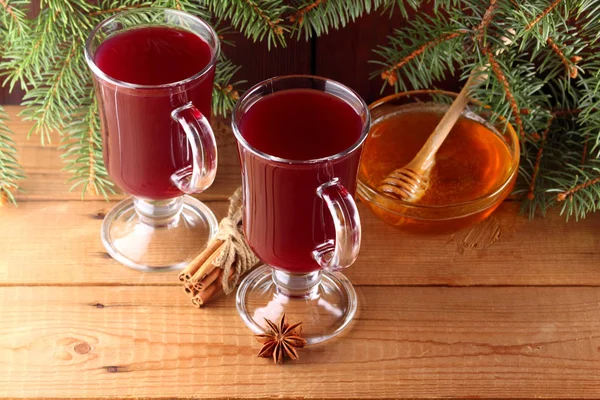 Mulled wine and Christmas tree branches on wooden boards. Christmas mulled wine, cinnamon sticks, anise and honey. Alcoholic drink of wine, fruit and honey. Festive drink on wooden boards