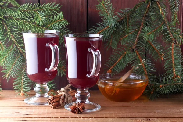 Mulled wine and Christmas tree branches on wooden boards. Christmas mulled wine, cinnamon sticks, anise and honey. Alcoholic drink of wine, fruit and honey. Festive drink on wooden boards