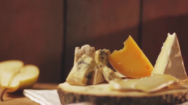 Různé typy sýrů a kouskem hrušky na dřevěných deskách. Niva, camembert a tvrdý sýr na dřevěný podstavec. Výběr sýrů a zralé hrušky