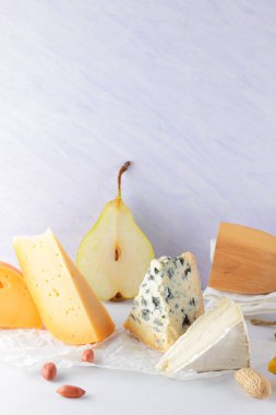 Çeşitli peynirler, armut ve beyaz zemin üzerine fıstık. Mavi peynir ve camembert parşömen kağıt üzerinde. Süt ürünleri ve meyveler kahvaltıda. Sağlıklı gıda. Kopya alanı