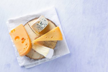 Camembert, sert sarı peynir ve mavi peynir ahşap tahta üzerinde. Beyaz peçete üzerinde çeşitli peynir parçalarını. Dorblu ve yumuşak peynir minimalizm tarzı. Organik süt ve süt ürünleri