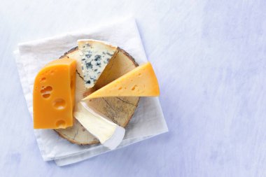 Camembert, sert sarı peynir ve mavi peynir ahşap tahta üzerinde. Beyaz peçete üzerinde çeşitli peynir parçalarını. Dorblu ve yumuşak peynir minimalizm tarzı. Süt ürünleri