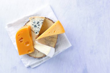 Camembert, sert sarı peynir ve mavi peynir ahşap tahta üzerinde. Beyaz peçete üzerinde çeşitli peynir parçalarını. Dorblu ve yumuşak peynir minimalizm tarzı. Süt ürünleri