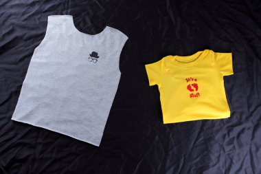 Dikiş el yapımı çizim ile çocuk t-shirt. Gri ve sarı kumaş koyu arka plan üzerine. Terzilik işlemi. Gri ve sarı kumaş resimlerle. Siyah bir arka plan üzerinde t-shirtler için boşluklar