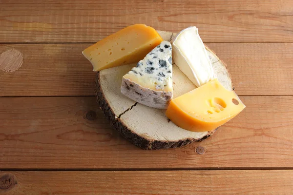 Assortment of cheeses on wooden boards. Camembert, hard yellow cheese, dorblu on wooden stand. Top view