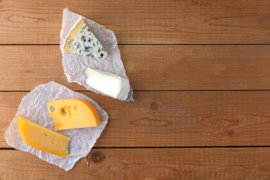 Peynir ahşap kurullarında türleri. Camembert, sert sarı peynir, parşömen kağıt üzerinde dorblu. Üstten görünüm