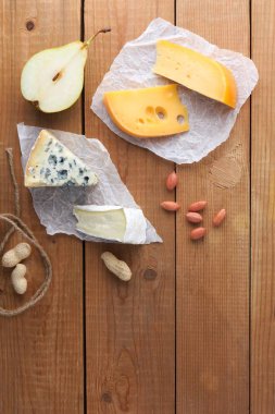 Peynir, armut ve parşömen kağıt üzerine fıstık ürün yelpazesine. Camembert, sert sarı peynir, dorblu ahşap kurullarında. Süt ürünleri, yarım armut ve fındık
