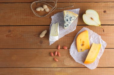 Peynir, armut ve parşömen kağıt üzerine fıstık ürün yelpazesine. Camembert, sert sarı peynir, dorblu ahşap kurullarında. Süt ürünleri, yarım armut ve fındık