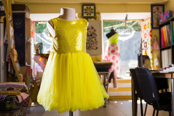 Yellow children\'s dress with sparkles on mannequin. Little yellow dress in studio. Sewing women\'s handmade children\'s clothing. Yellow baby clothes
