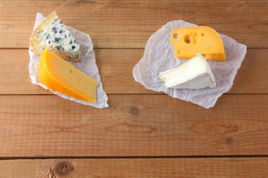 Peynir ahşap kurullarında. Camembert, sert sarı peynir, parşömen kağıt üzerinde dorblu. Üstten görünüm