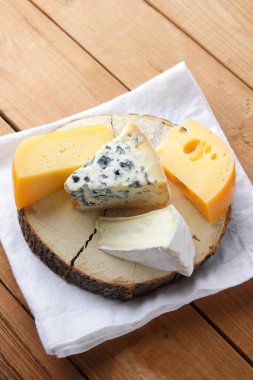 Beyaz bez üzerine peynir. Camembert, sert sarı peynir, tahta tahtalar üzerinde dorblu. Beyaz peçete üzerinde süt ürünleri