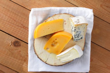 Beyaz bez üzerine peynir. Camembert, sert sarı peynir, tahta tahtalar üzerinde dorblu. Beyaz peçete üzerinde süt ürünleri