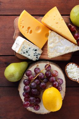 Tahta tahtada sert peynir, mavi peynir ve süzme peynir. Ahşap bir arka plan üzerinde peynir ve bal farklı türleri. Süt ürünleri, armut, limon ve üzüm. Üstte görüntü