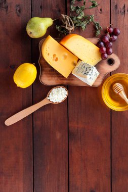 Tahta tahtada sert peynir, mavi peynir ve süzme peynir. Ahşap bir arka plan üzerinde peynir ve bal farklı türleri. Süt ürünleri, armut, limon ve üzüm. Üstte görüntü