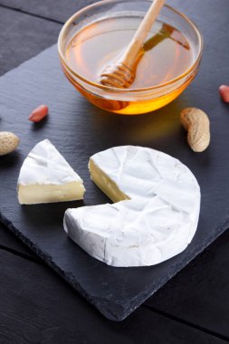 Camembert ve siyah arduvaz tahtası tatlım. Yumuşak peynir küf ve fıstık siyah bir arka plan ile. Peynir ve fındık bir taş gemide. Kopya alanı