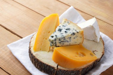 Beyaz kumaş üzerine peynir. Camembert, sert sarı peynir, dorblu ahşap kurullarında. Süt ürünleri Beyaz peçete üzerinde