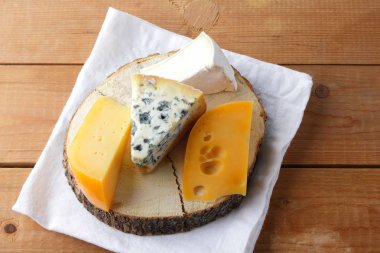 Beyaz kumaş üzerine peynir. Camembert, sert sarı peynir, dorblu ahşap kurullarında. Süt ürünleri Beyaz peçete üzerinde