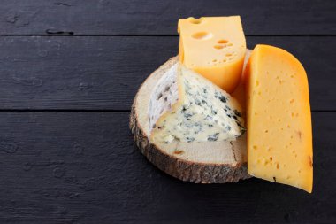 Sert peynir ve mavi peynir ahşap stand. Peynir siyah kurullarında farklı türleri. İsviçre peyniri ve dorblu koyu arka plan üzerinde