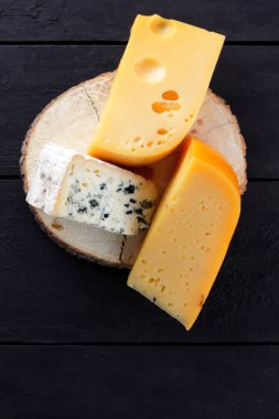 Sert peynir ve mavi peynir ahşap stand. Peynir siyah kurullarında farklı türleri. İsviçre peyniri ve dorblu koyu arka plan üzerinde