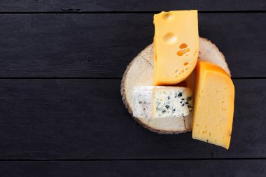 Sert peynir ve mavi peynir ahşap stand. Peynir siyah kurullarında farklı türleri. İsviçre peyniri ve dorblu koyu arka plan üzerinde