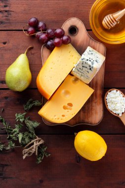 Sert peynir, mavi peynir ve peynir ahşap tahta üzerinde. Peynir ve bal ahşap arka plan üzerinde farklı türleri. Süt ve süt ürünleri, armut, limon ve üzüm. Üstten görünüm