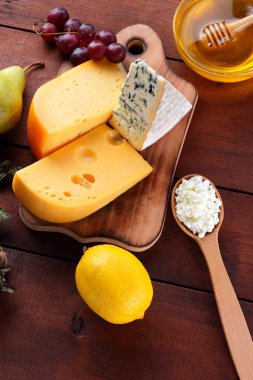 Sert peynir, mavi peynir ve peynir ahşap tahta üzerinde. Peynir ve bal ahşap arka plan üzerinde farklı türleri. Süt ve süt ürünleri, armut, limon ve üzüm. Üstten görünüm
