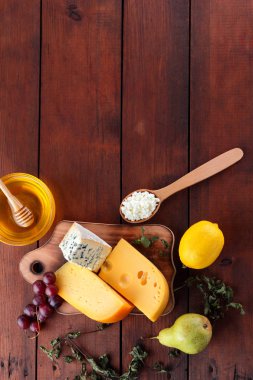 Sert peynir, mavi peynir ve peynir ahşap tahta üzerinde. Peynir ve bal ahşap arka plan üzerinde farklı türleri. Süt ve süt ürünleri, armut, limon ve üzüm. Üstten görünüm