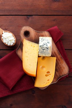 Sert peynir, mavi peynir ve peynir ahşap tahta üzerinde. Peynir kırmızı peçete üzerinde farklı türleri. Süt ürünleri ve ahşap zemin üzerine limon. Üstten görünüm