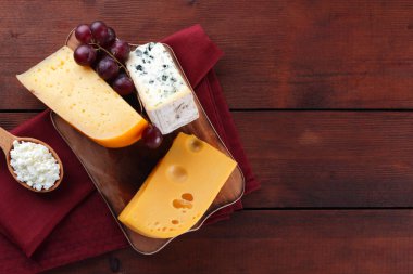 Sert peynir, mavi peynir ve peynir ahşap tahta üzerinde. Peynir kırmızı peçete üzerinde farklı türleri. Süt ürünleri ve ahşap zemin üzerine limon. Üstten görünüm