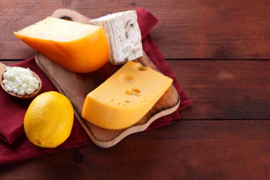 Sert peynir, mavi peynir ve peynir ahşap tahta üzerinde. Peynir kırmızı peçete üzerinde farklı türleri. Süt ürünleri ve ahşap zemin üzerine limon. Üstten görünüm
