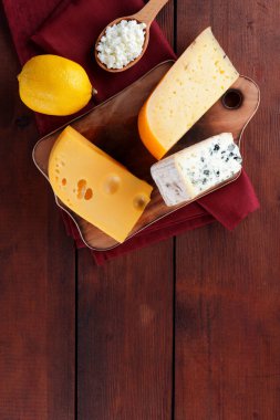 Sert peynir, mavi peynir ve peynir ahşap tahta üzerinde. Peynir kırmızı peçete üzerinde farklı türleri. Süt ürünleri ve ahşap zemin üzerine limon. Üstten görünüm