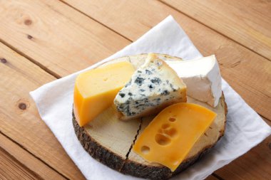 Beyaz kumaş üzerine peynir. Camembert, sert sarı peynir, dorblu ahşap kurullarında. Süt ürünleri Beyaz peçete üzerinde