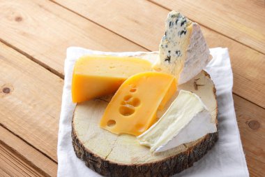 Beyaz kumaş üzerine peynir. Camembert, sert sarı peynir, dorblu ahşap kurullarında. Süt ürünleri Beyaz peçete üzerinde