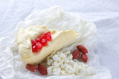 Camembert ve süzme peynir beyaz kumaş üzerine. Çeşitli peynir, fıstık ve beyaz arka plan üzerinde tatlım. Peynir, nar taneleri ve fındık. Sağlıklı gıda